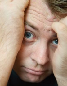 shy young man hiding his face in his hands