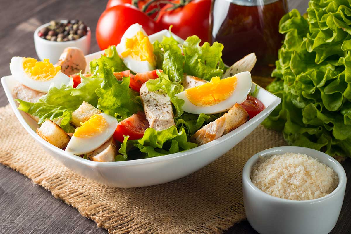 Ciotola con ceaser salad ricca di ingredienti colorati