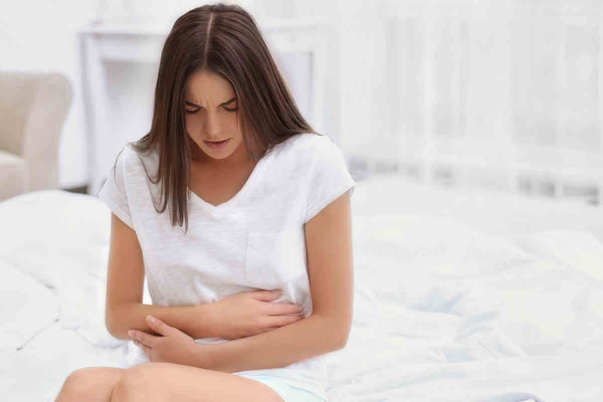 Giovane donna che soffre di dolori addominali causati dal ciclo
