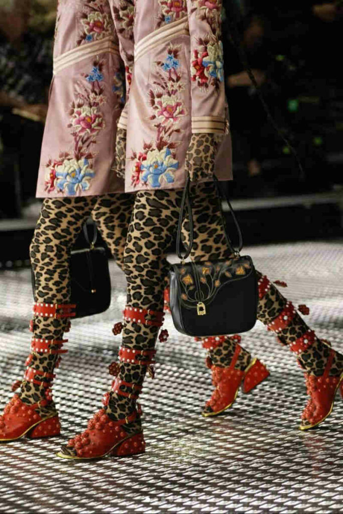 modelle sfilata Gucci con collant leopardati e scarpe rosse
