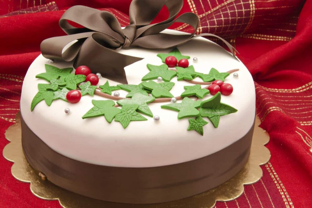torta a tema natalizio di colore bianco e marrone con alberi di natale sopra e un fiocco marrone