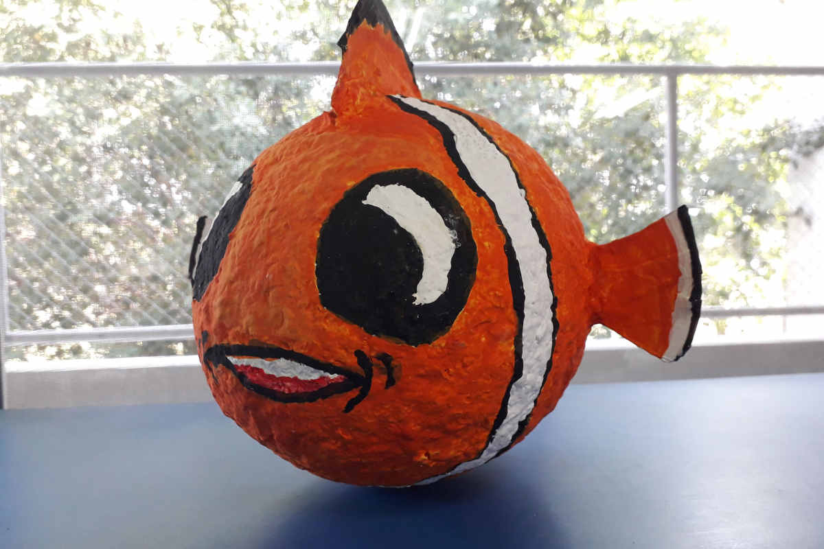 pesce pagliaccio finto di colore bianco, arancio e nero, creato con la cartapesta