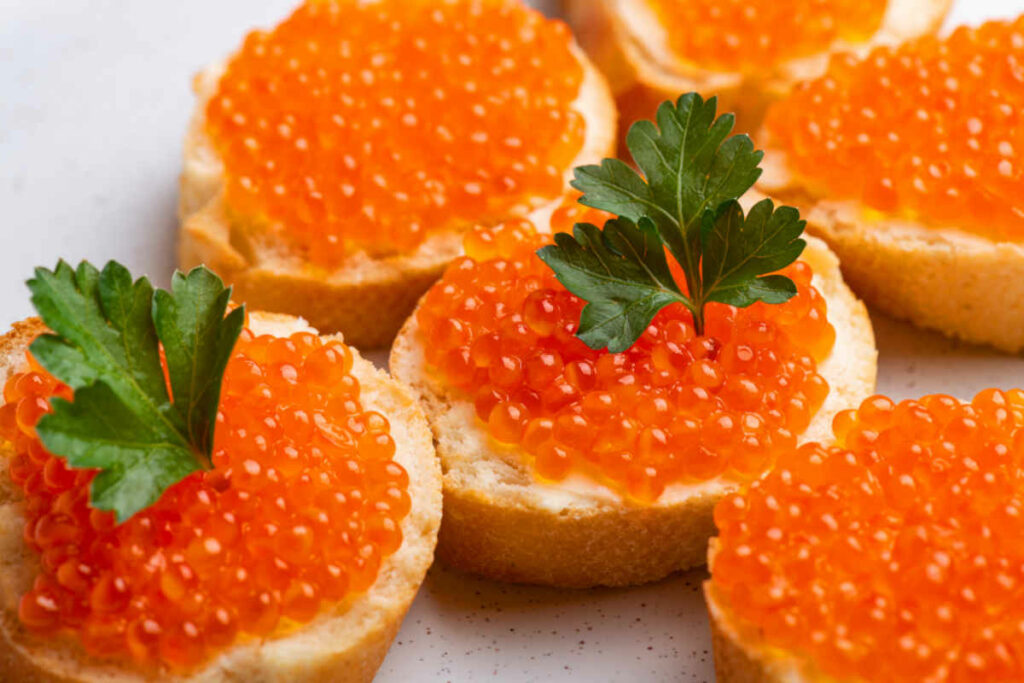 Tartine con formaggio, uova di salmone e decorate con del prezzemolo