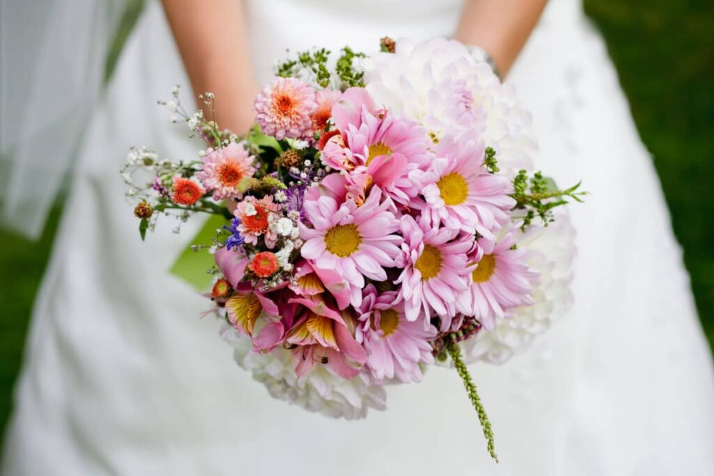 mani di sposa con un bouquet di fiori rosa 