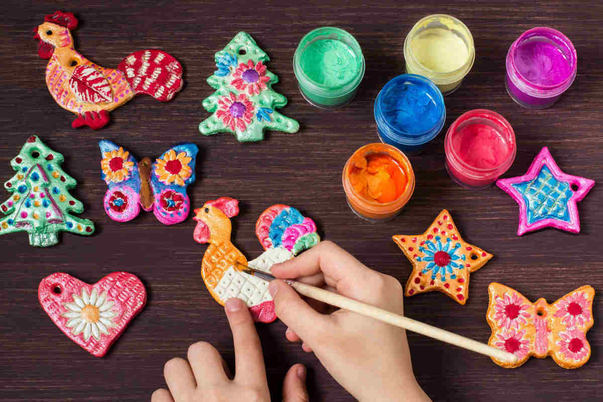 mani di bambina che colorano oggetti fatti con la pasta di sale