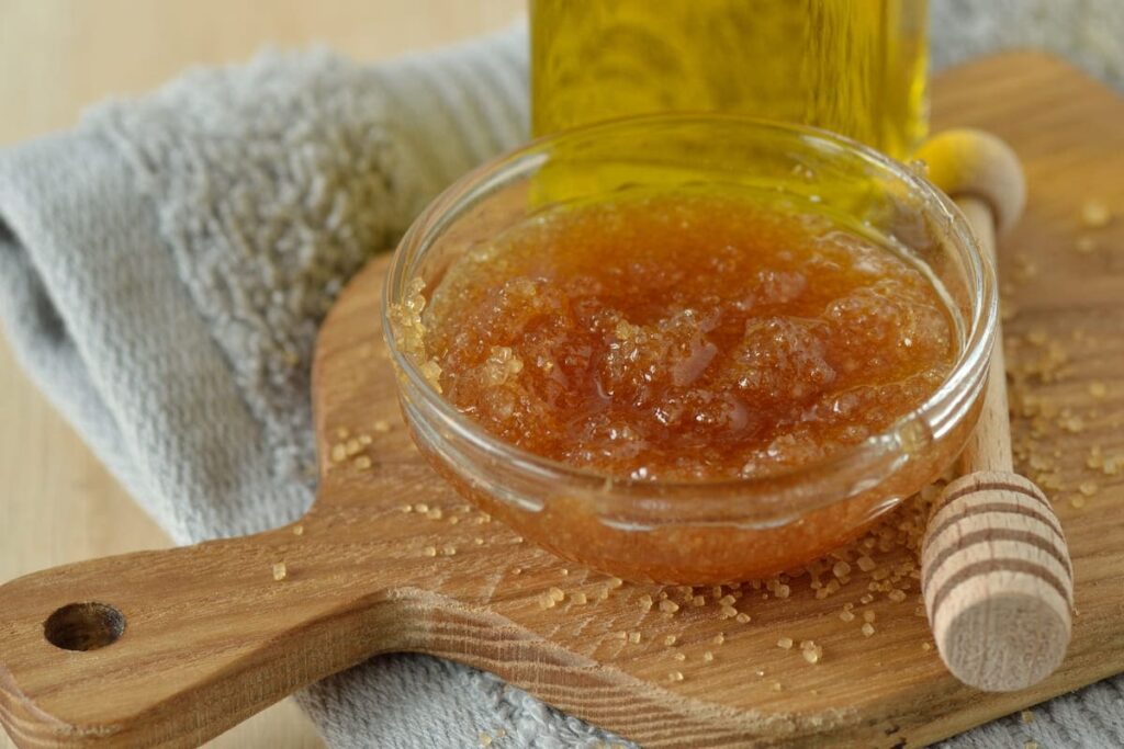 ingredienti per scrub capelli sfibrati con miele e zucchero di canna su un tagliere di legno