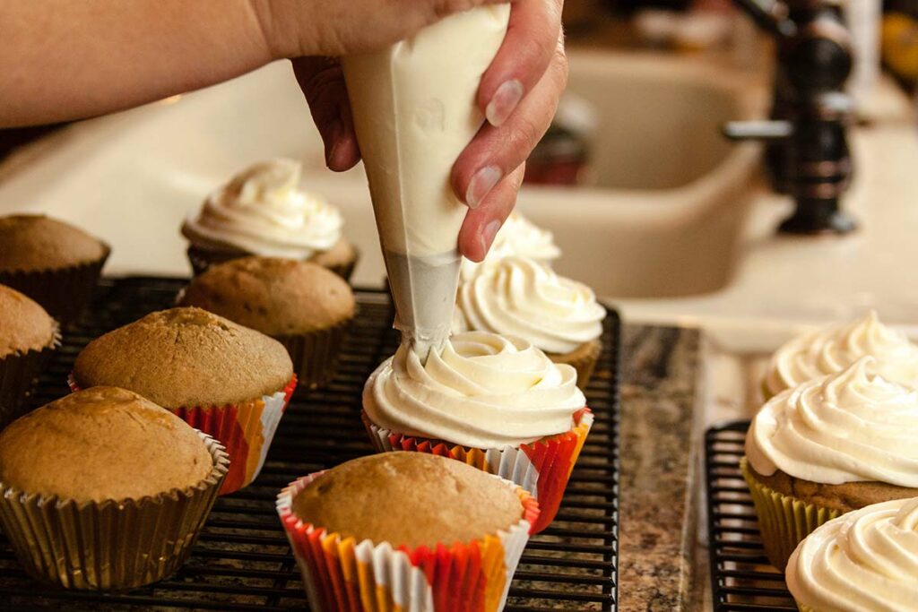 Donna che decora i cupcake con una crema al burro