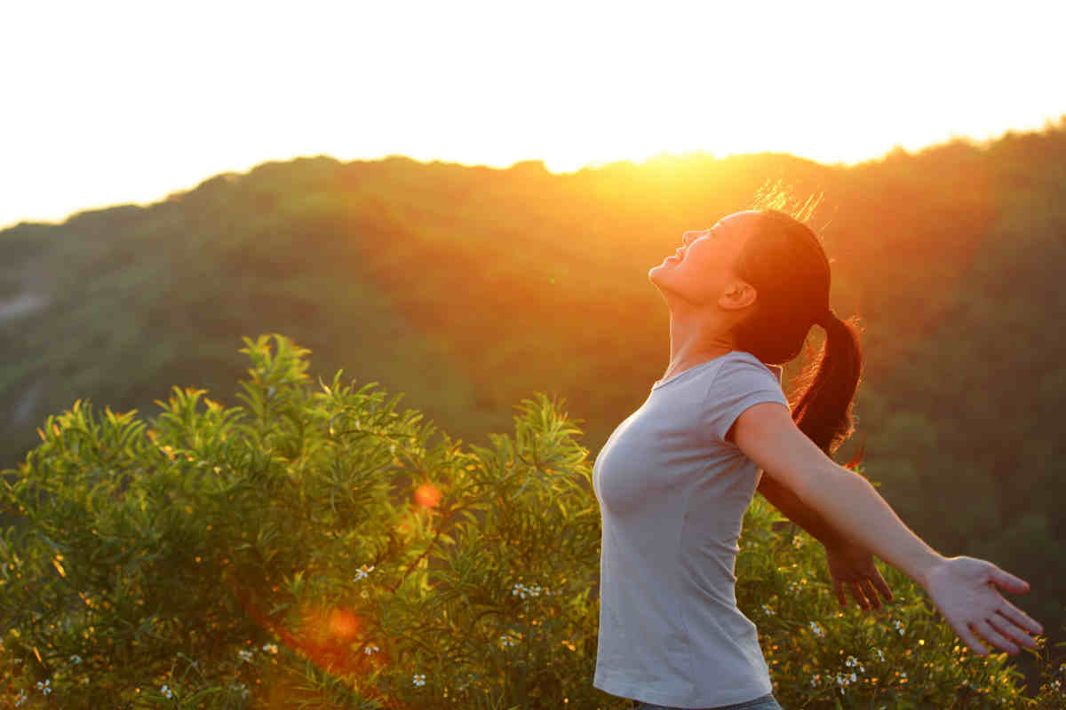ragazza con braccia aperte, all'aria aperta con l'alba alle spalle