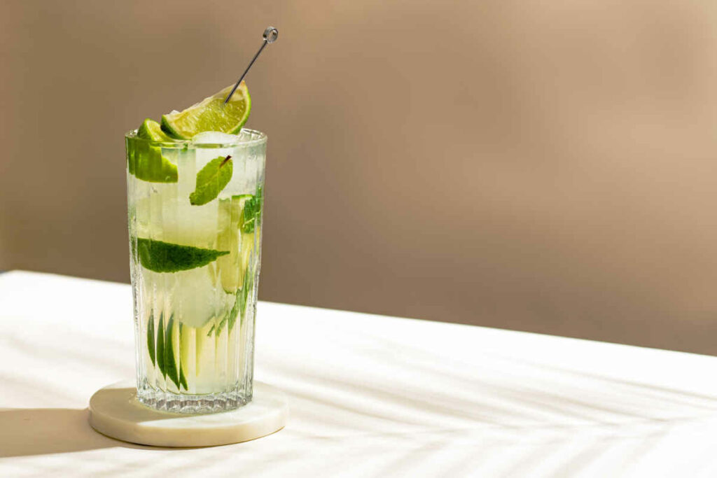 immagine di mojito cocktail in bicchiere di vetro con cannuccia con rum, ghiaccio e lime  ru
