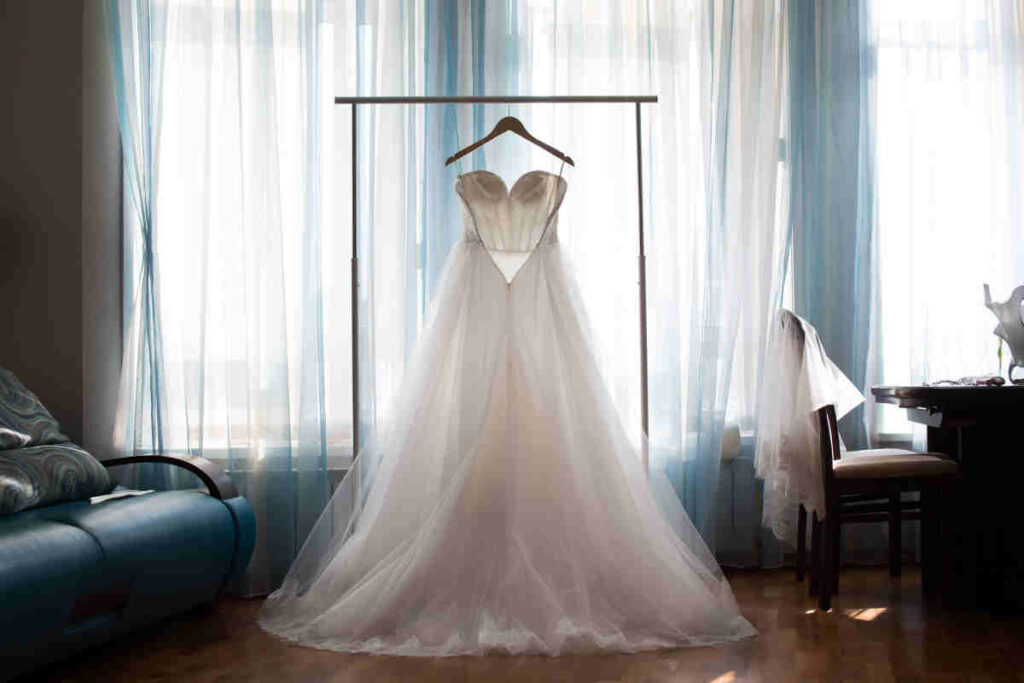 abito da sposa in una stanza, appeso con finestra sullo sfondo 