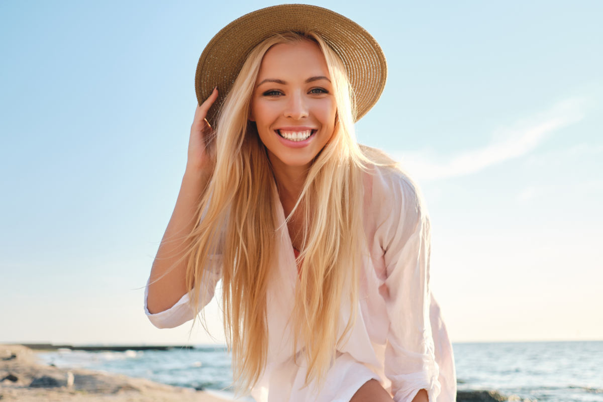 giovane donna al mare con capelli biondi e cappello