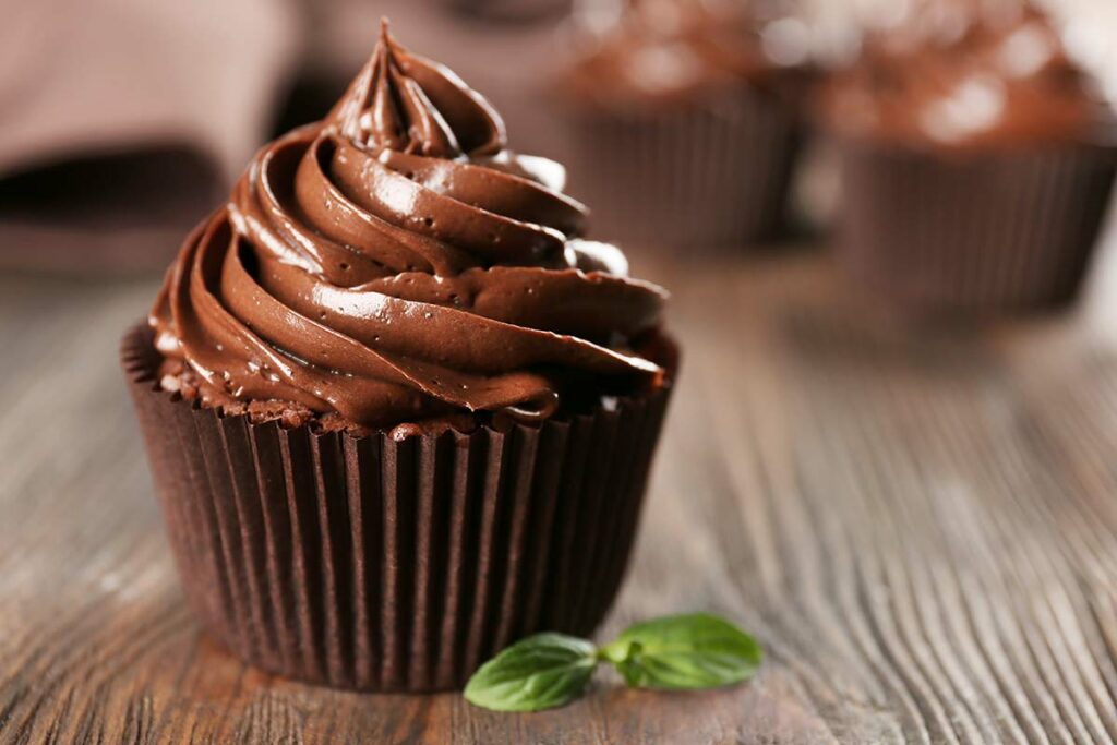 Cupcake al cioccolato con frosting al cioccolato appoggiato su di un tavolo di legno