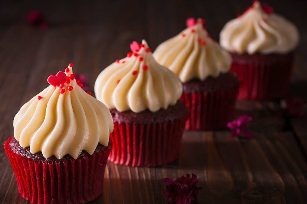 Primo piato di 4 red velvet cupcake appoggiati su di un tavolo di legno