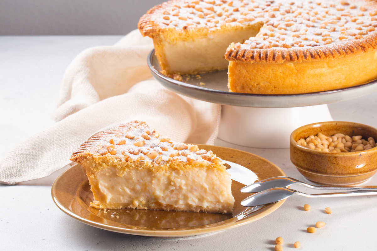 fetta di torta con crema e pinoli servita su un piatto