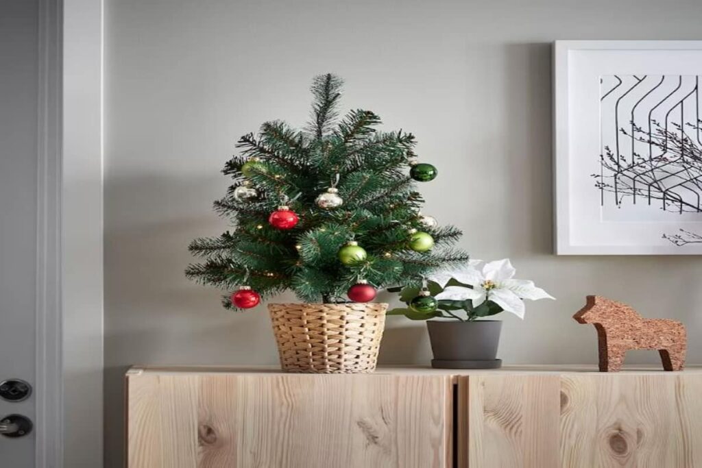 albero di natale piccolo, con palline e vaso, poggiato su un mobile in legno