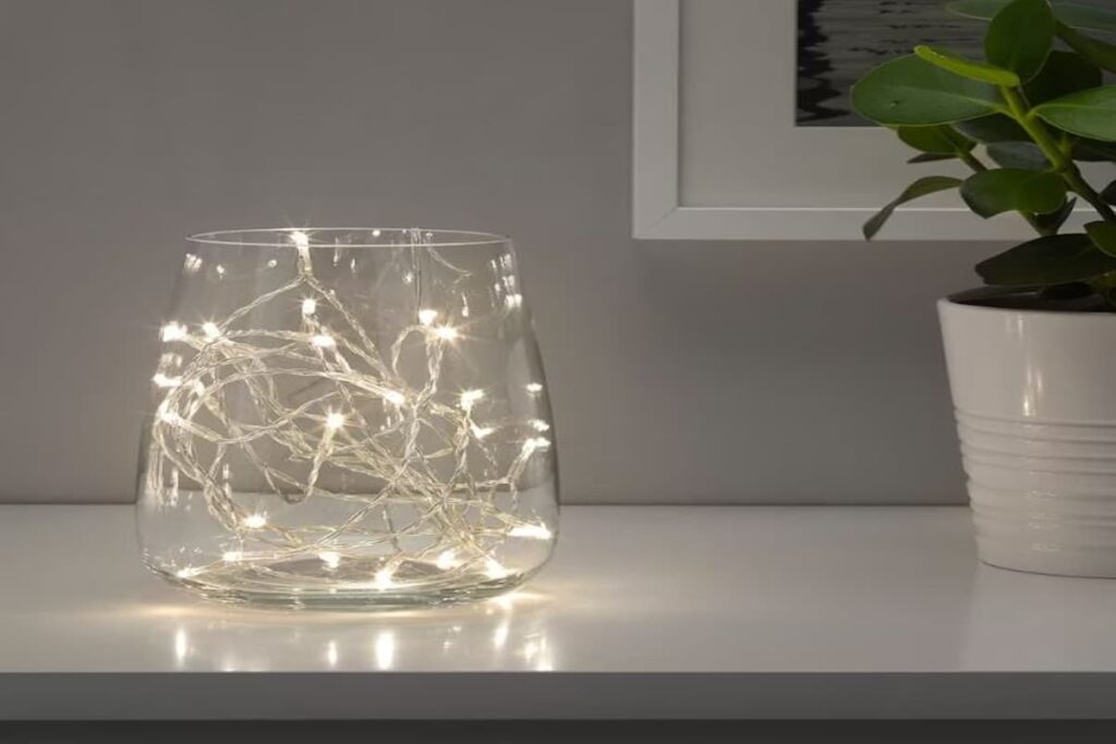 vaso trasparente poggiato su un mobile con luci calde LED all'interno