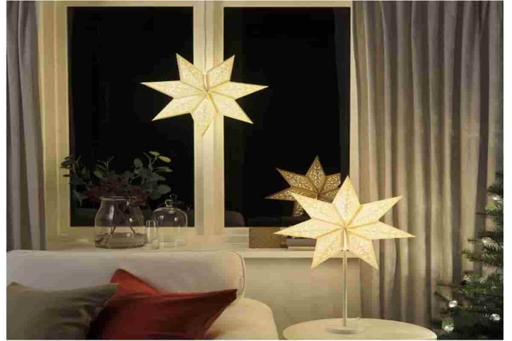 finestra di un soggiorno, con due stelle di natale che emanano una luce soffusa e calda 