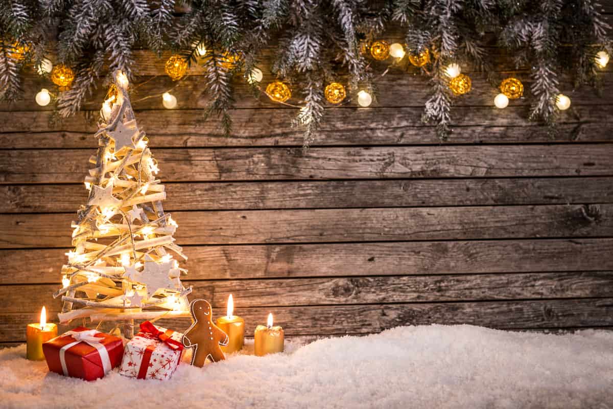 albero di natale in legno con sfondo di legno scuro, lucine calde e regali di piccole dimensioni sotto l'albero