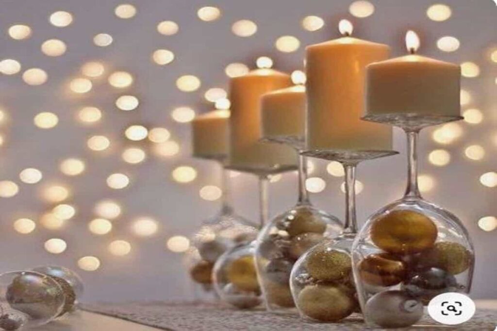 centrotavola con calici di vino usati come decorazioni, con palline di natale al loro interno e candele accese