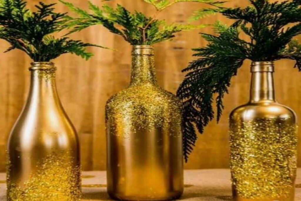 bottiglie dorate e glitterate con foglie verdi all'interno, perfette per un centrotavola di capodanno