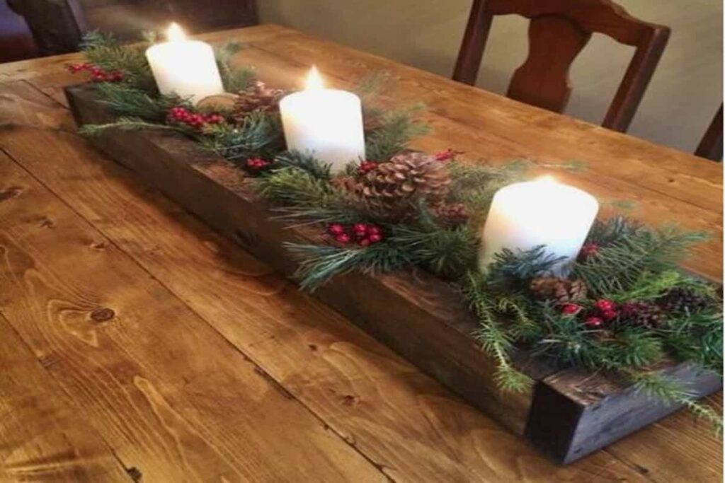 centrotavola in legno con candele bianche e decorazioni con aghi di pino, su tavolo in legno