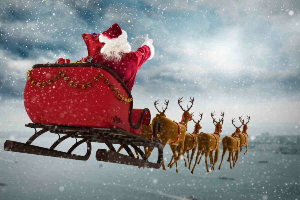 uomo vestito di rosso rappresentante babbo natale su una slitta con le renne