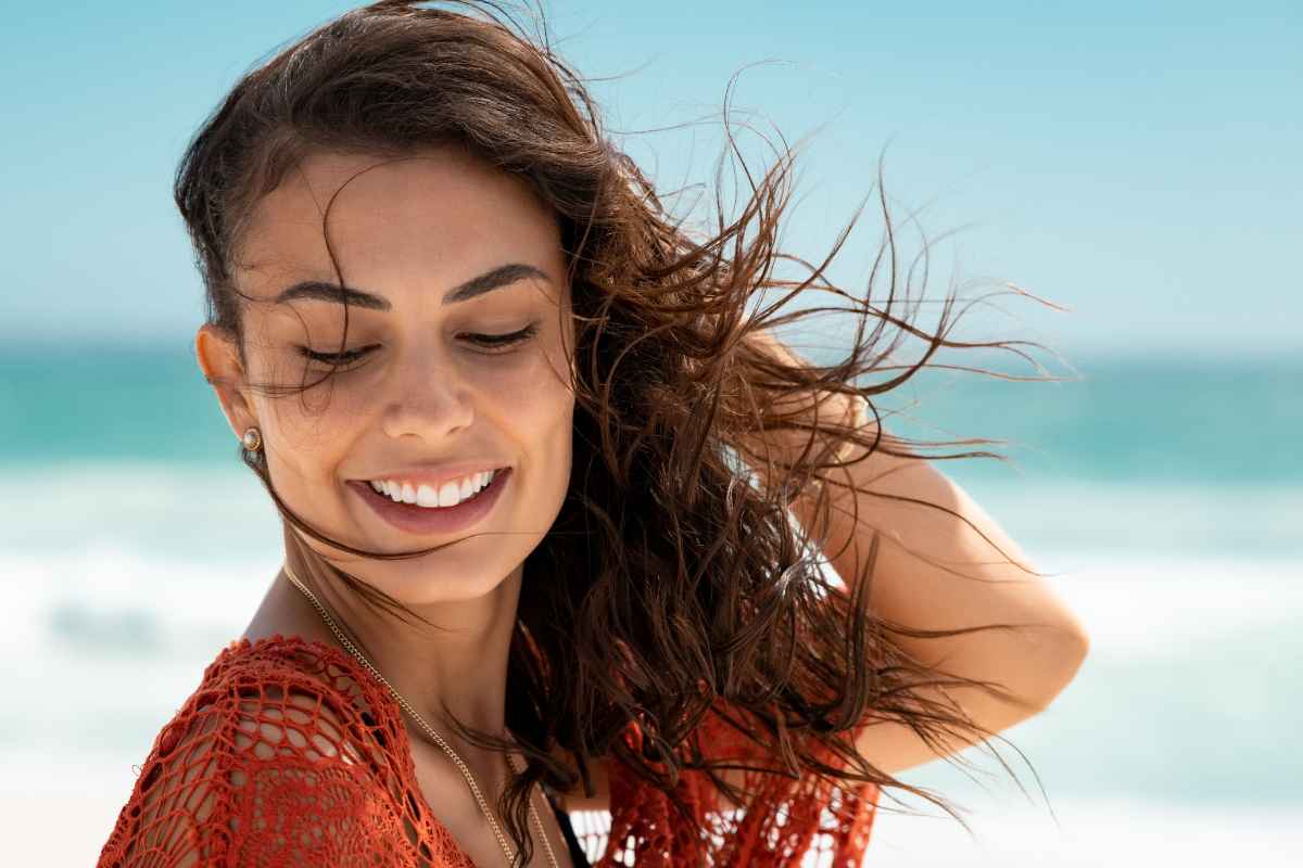 Primo piano di giovane donna con capelli al vento al mare