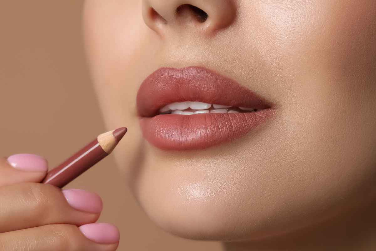 Ragazza che si mette una matita labbra della stessa tonalità del rossetto