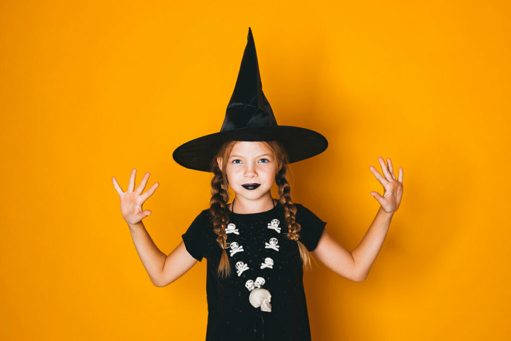 bambina con cappello da strega, vestito nero e rossetto nero per halloween 