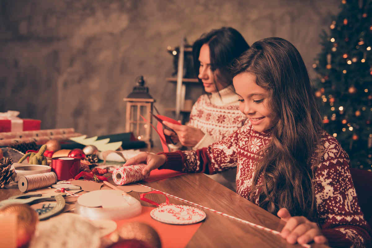 mamma e figlia sorridenti svolgono dei lavoretti creativi durante le festività natalizie