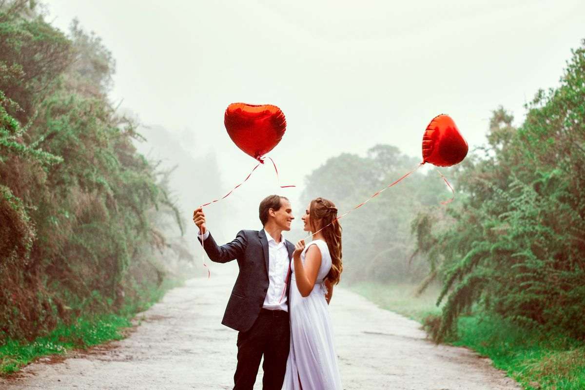 coppia felice in strada con palloncini a forma di cuore