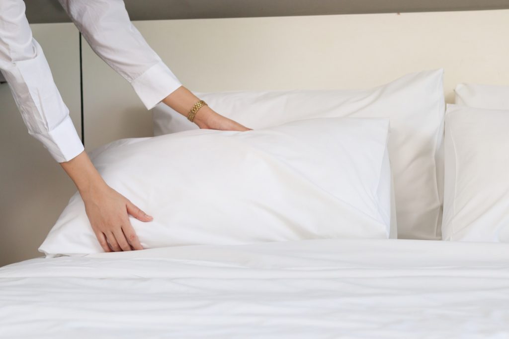 donna sistema cuscino sul letto