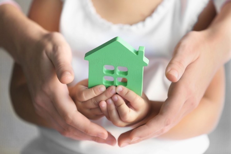 bambino con in mano una casetta di legno verde