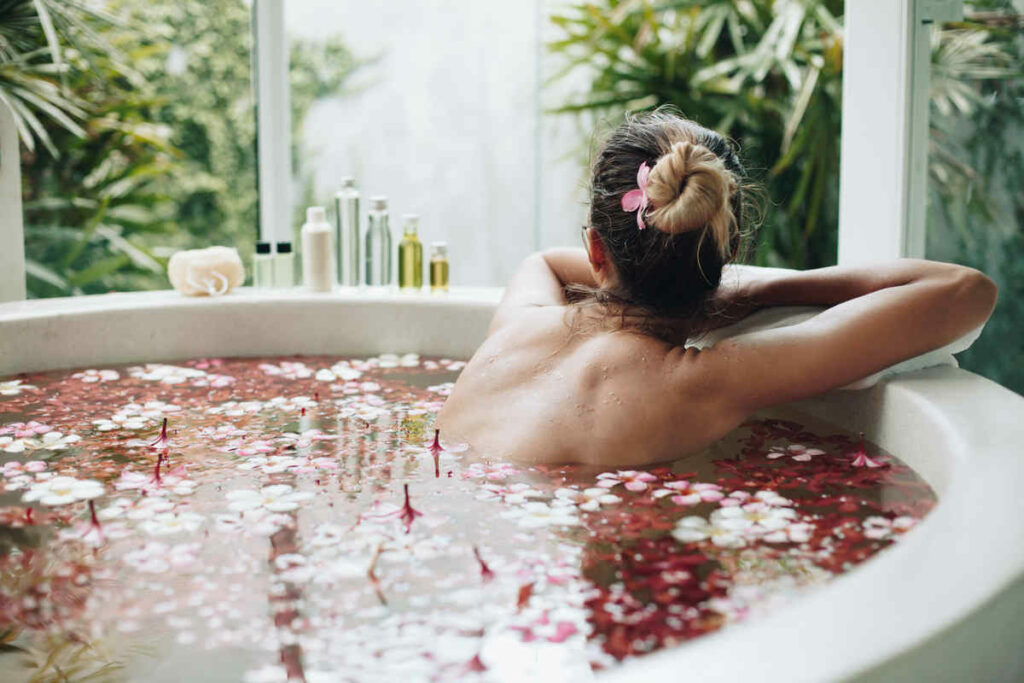 ragazza di schiena dentro una vasca con petali di fiori