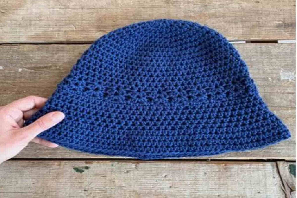 cappello di colore blu, poggiato su un tavolo in legno, all'uncinetto