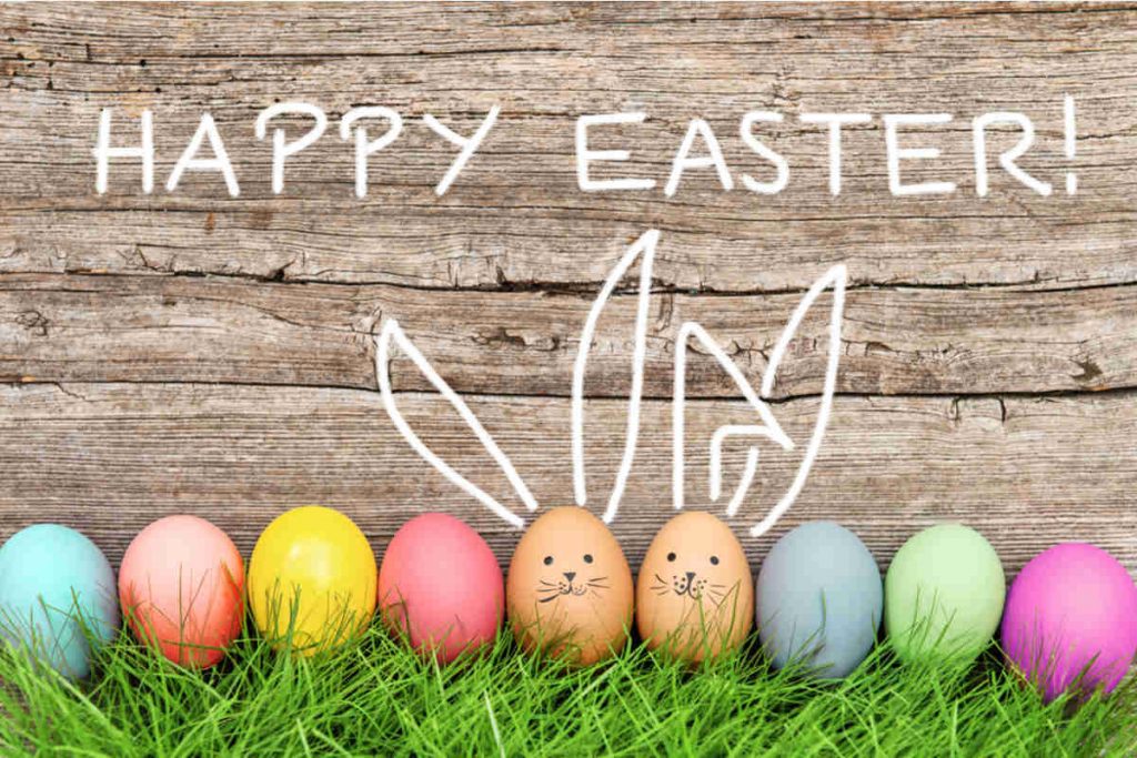 uova colorate su prato verde con scritta happy easter