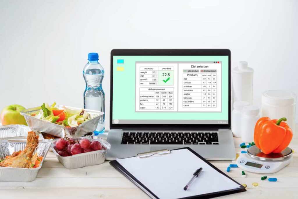 computer con piano alimentare, carta e penna, bottiglia d'acqua, e spuntini da mangiare