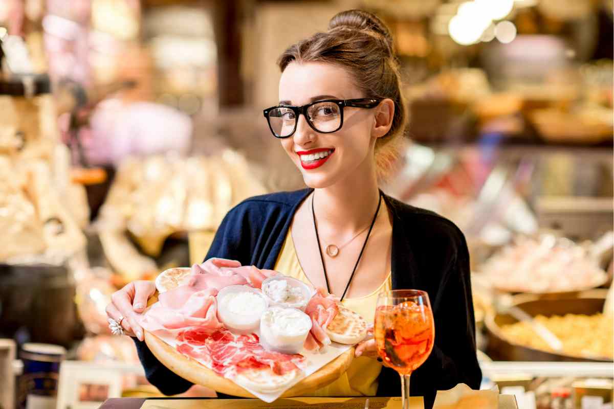 ragazza regge un tagliere per l'aperitivo a dietra