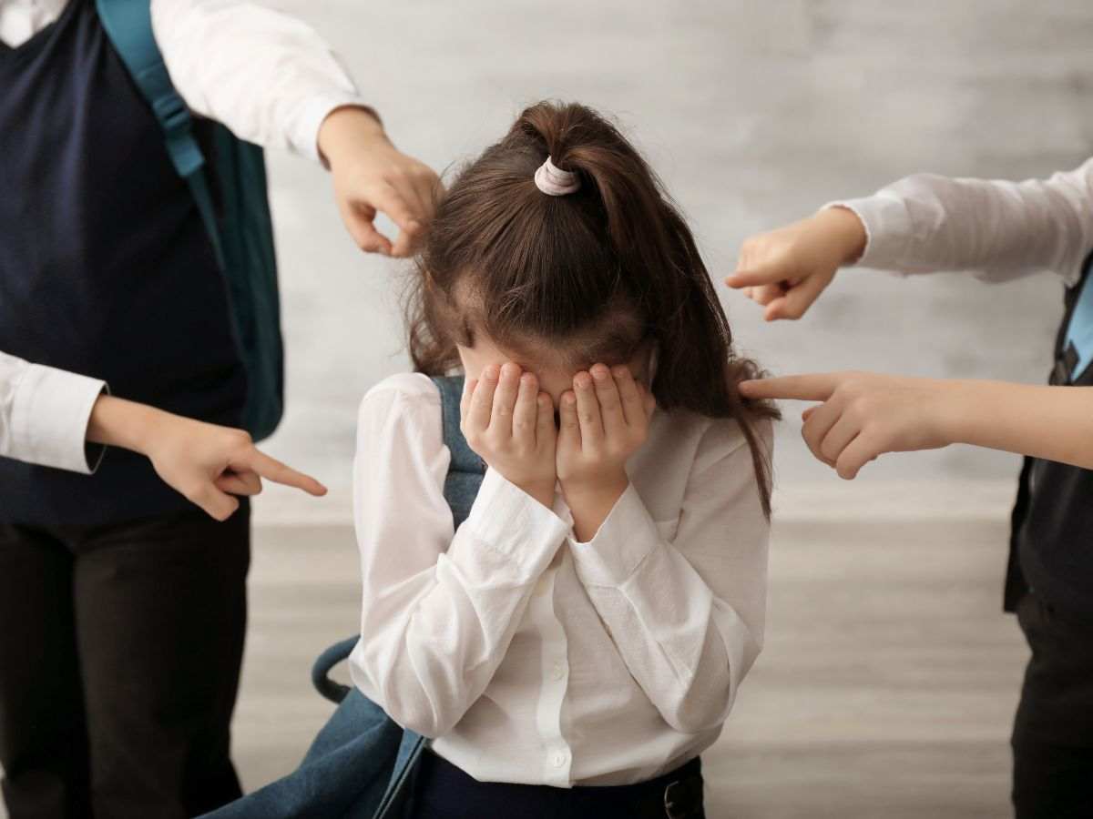 bambina che si copre la faccia con le mani
