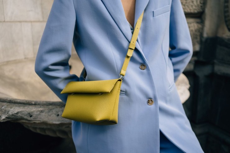 ragazza con spolverino azzurro chiaro e borsa gialla