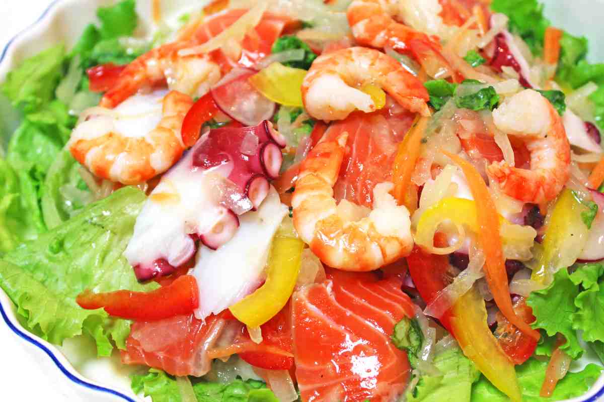 un piatto di insalata di mare mista su foglia di lattuga che è uno degli antipasti freddi estivi veloci da preparare con facilità