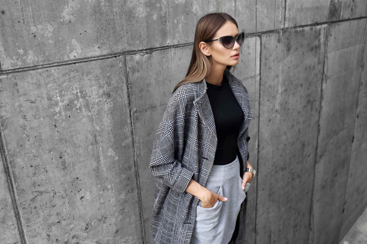 donna con cappotto color tortora e occhiali da sole neri
