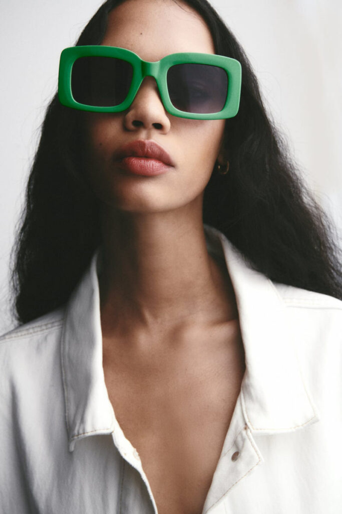 donna con camicia bianca e occhiali da sole montatura verde