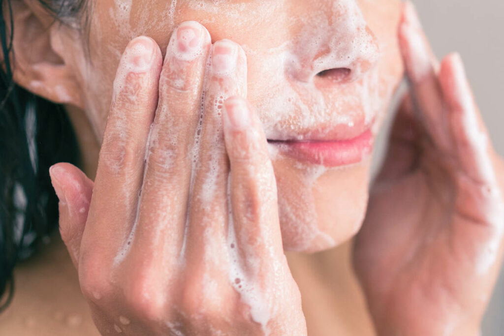 ragazza che si lava il viso con un detergente saponato