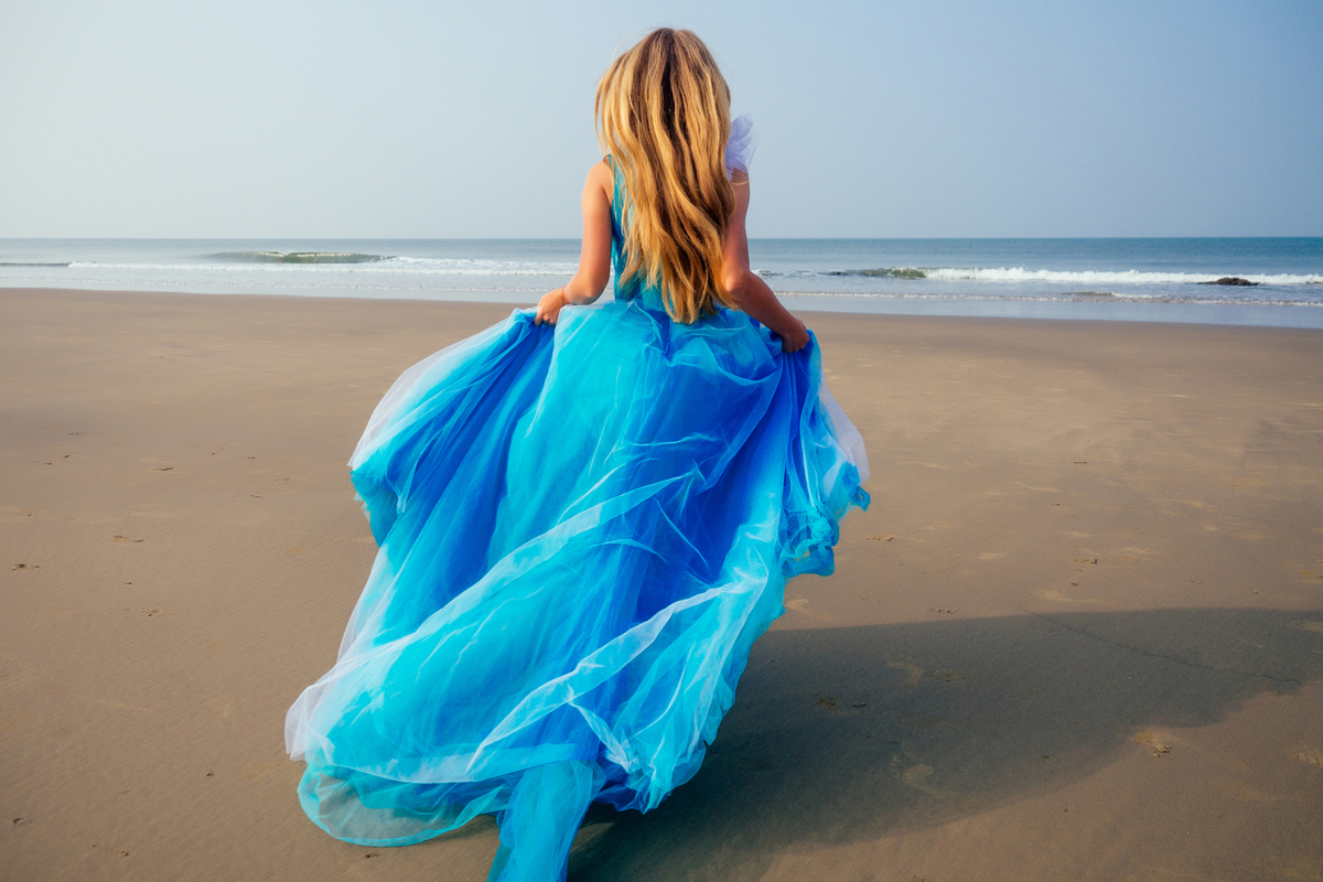 Ragazza con un abito lungo blu in spiaggia