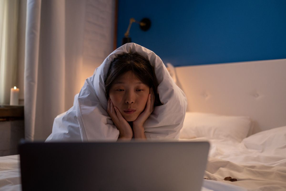 ragazza che guarda un film al computer sdraiata sul letto