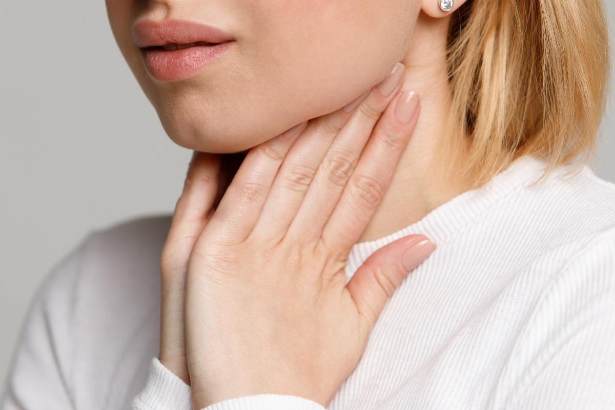 Ragazza bionda che si tocca il collo con entrambe le mani