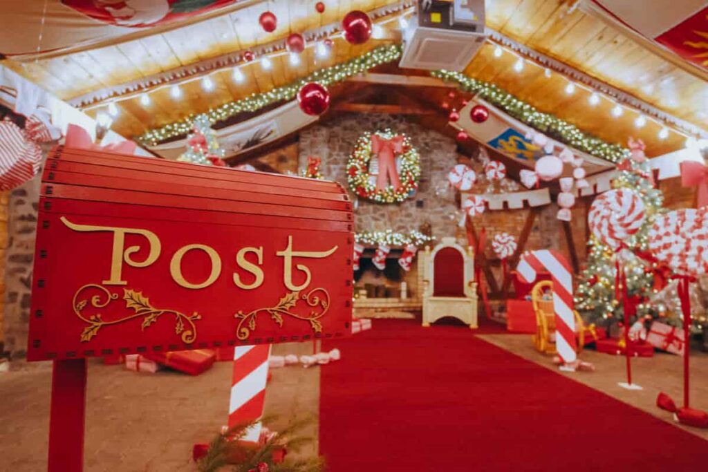 sala interna del villaggio di babbo natale con decorazioni natalizie di colore bianco e rosso e cassetta della posta in primo piano