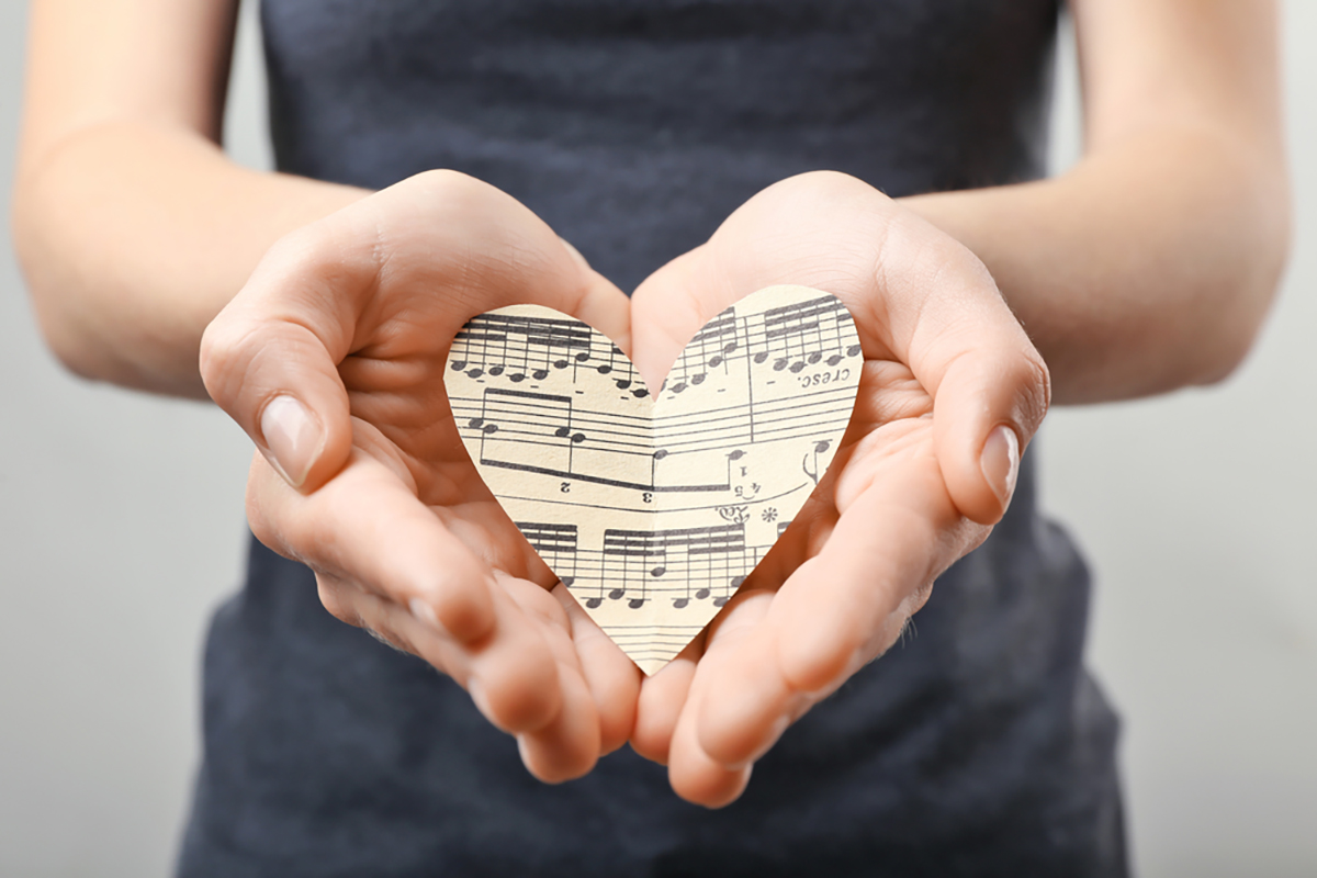 Ragazza con un cuore fatto di carta di spartito