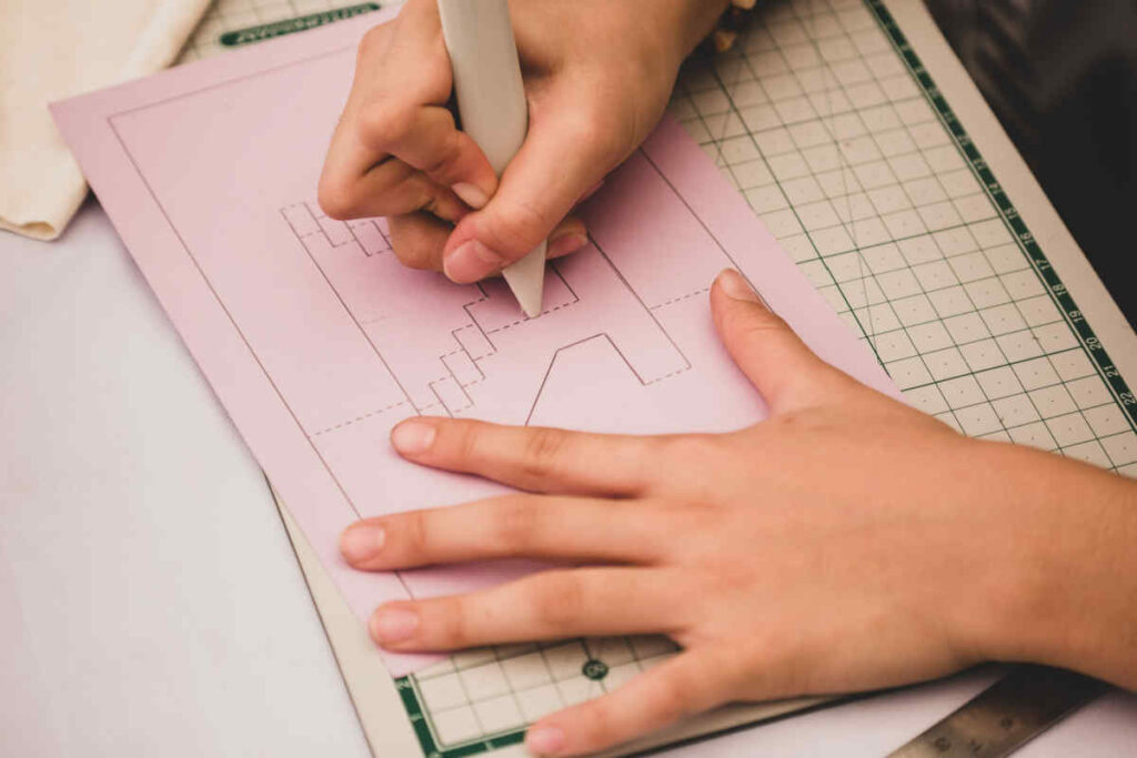 mani di bambino che disegnano su un foglio di colore rosa per realizzare dei lavoretti fai da te